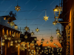 mexico, san miguel de allende. lighted stars suspended over a street at sunset.
