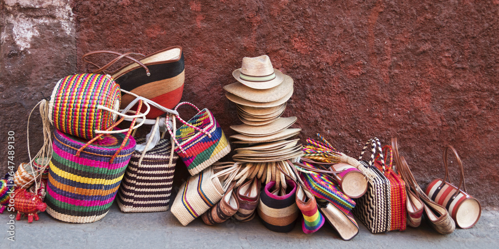woven souvenirs on display on a sidewalk against a wall; san miguel de allende, guanajuato, mexico