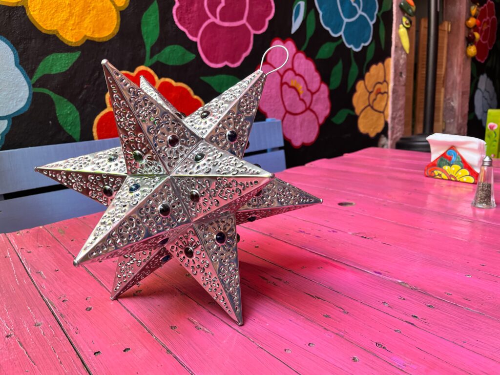 mexican tin star on pink picnic table with floral background san miguel de allende mexico artisan crafts